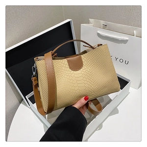 Macro view of khaki crocodile texture on leather tote bag with brown handle detail