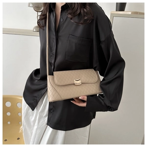 Modèle portant un sac bandoulière beige matelassé avec fermoir doré et bandoulière fine