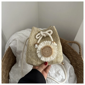 Détail du sac seau en paille tissée avec fleur de soleil et fermeture par cordon en coton