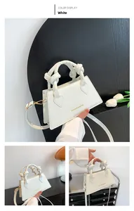Détail du sac à main blanc gaufré crocodile avec poignée nouée et lettrage doré chic