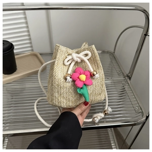 Detail of straw bucket bag featuring 3D pink fabric flowers and cotton rope strap