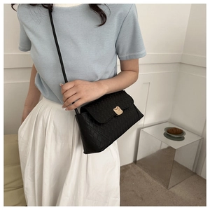 Détail d'un sac bandoulière noir avec cuir texturé à chevrons et fermoir en métal doré