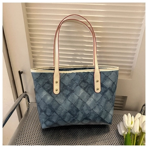Détail du sac cabas matelassé bleu denim avec bandoulières crème et bords rouges