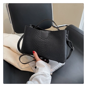 Close-up of black crocodile pattern leather tote bag with top handle and metal zipper detail