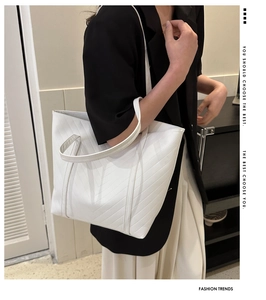 Modella che indossa una borsa tote bianca con trama trapuntata a V per look ufficio
