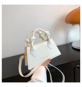 Détail du sac blanc motif crocodile avec poignée nouée et finitions métalliques dorées