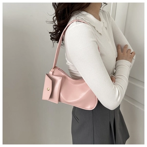 Detail of pink hobo shoulder bag with matching mini pouch on a minimalist background