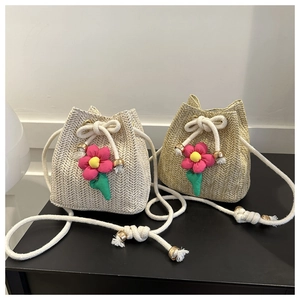 Detail of woven straw bucket bag showing herringbone texture and colorful 3D flower charms