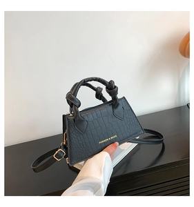 Détail d'un sac à main noir en crocodile avec poignées nouées et boucles dorées