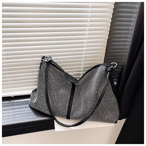 Macro detail of the sparkling rhinestone surface and silver metal rings on the black tote bag
