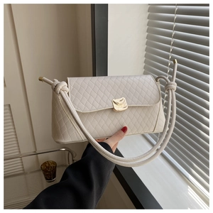 Détail du sac à bandoulière matelassé crème avec boucle dorée et sangle à nœuds décoratifs
