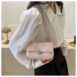 Detail of pink quilted PU leather crossbody bag with silver chain strap on model