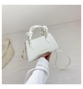Gros plan d'un sac à main blanc motif crocodile avec une poignée nouée élégante