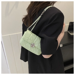 Detail of light green quilted bag with silver chain strap and metal swivel lock on model