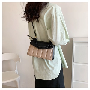 Detailed view of bicolor crossbody bag with quilted texture and knotted strap on model