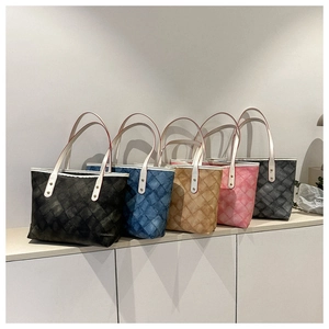 Cinq cabas matelassés de couleurs variées disposés sur une étagère blanche épurée