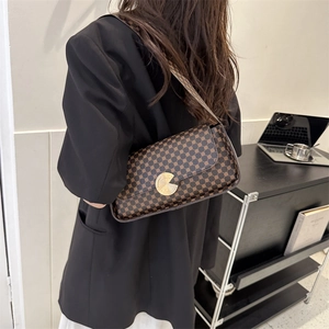 Sac bandoulière vintage avec boucle dorée porté par un mannequin dans un bureau minimaliste