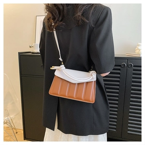 Close-up of contrast color handbag with white flap and caramel pleated leather details