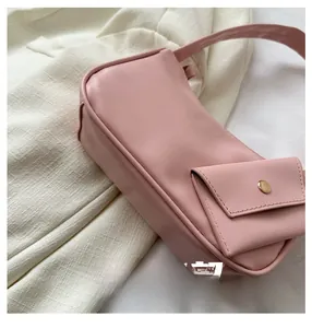 Detailed side view of pink shoulder bag with mini pocket and gold metallic clasp