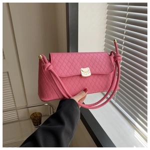 Détail d'un sac à bandoulière matelassé rose vif avec fermoir doré et bandoulière nouée