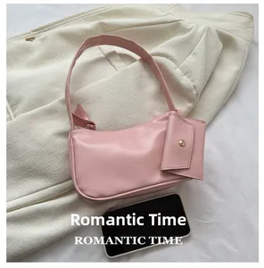 Pink crescent underarm bag with small coin purse shown next to a smartphone for scale