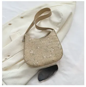 Detail of straw bucket bag featuring floral lace embroidery and brown leather strap