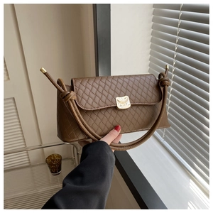 Détail du sac bandoulière marron en similicuir matelassé avec fermoir doré et nœud