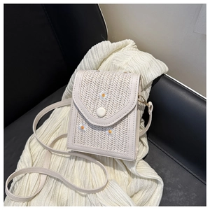Détail d'un sac bandoulière en paille crème avec broderie marguerite et boucle ronde chic