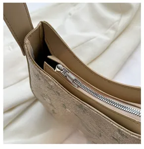 Detailed macro view of the smooth silver zipper and floral fabric on a woven straw bag