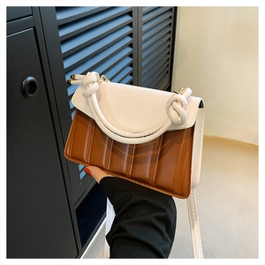 Detail shot of two-tone contrast bag with white knotted handle and brown pleated texture