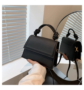Détail du sac à main en cuir noir mat avec poignées nouées et ferrures dorées élégantes