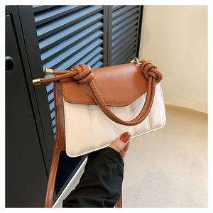 Detail of color-block shoulder bag with vertical stitching and knot handle design