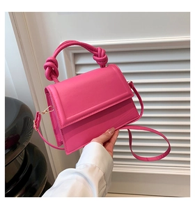 Détail du sac bandoulière en cuir rose vif avec poignée nouée et crochets dorés