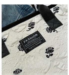 Macro detail of 3D embossed rose pattern on white canvas tote bag with fashion label