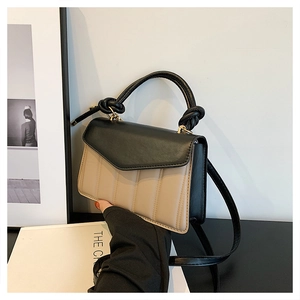 Detail of color-block handbag showing beige quilted texture and black knotted top handle