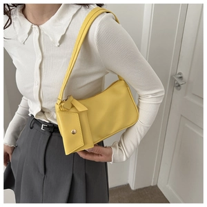 Detail of vibrant yellow underarm bag with a detachable mini envelope pouch on model