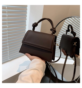 Détail d'un sac à main structuré en cuir marron foncé avec une poignée nouée