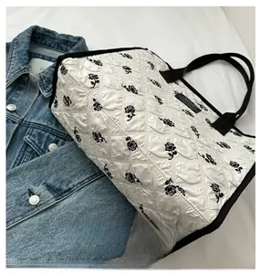 Detail of white quilted bubble fabric tote bag with black rose embroidery patterns