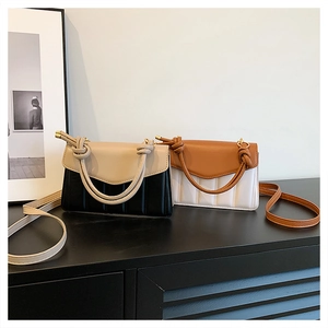 Detail of color block handbag showing vertical quilting and unique knotted handle design