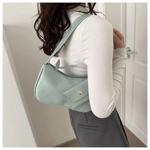 Detail view of a mint green minimalist underarm bag with gold buckle on a model