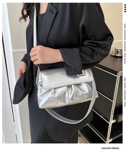 Détail du sac bandoulière argenté plissé avec texture métallique et fermoir doré sur blazer noir