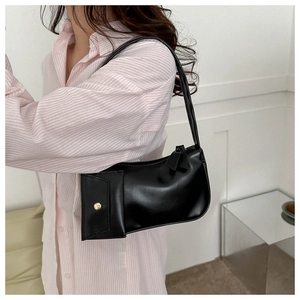 Detail of black faux leather shoulder bag with a gold buttoned envelope front pocket
