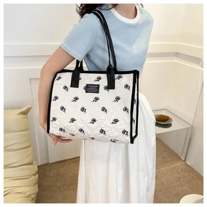 Close-up of black rose embroidery and FASHION tag on white canvas tote bag