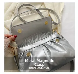 Détail d'un sac à main argenté plissé avec fermoir magnétique sécurisé en métal doré