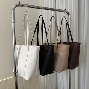 Borse tote in pelle PU trapuntata in quattro colori appese a un supporto di metallo