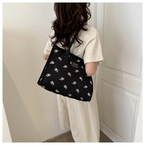 Close-up of black embroidered floral canvas tote bag with white roses and fashion label
