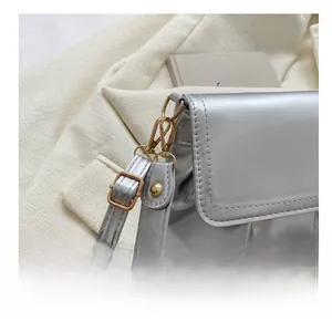 Détail du sac à main plissé argenté avec crochet doré et bandoulière en cuir chic