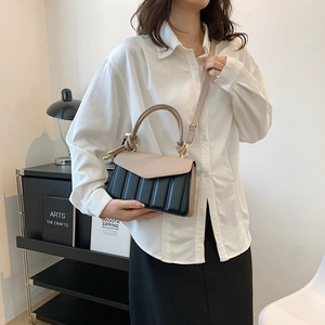 Chic beige and black contrast handbag with pleated texture shown on a female model