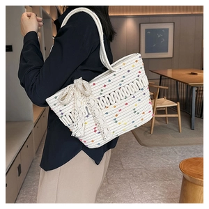 Close-up of woven straw tote bag with colorful dots and delicate white lace bow detail