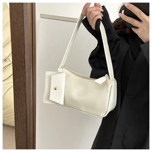 Detail of a minimalist white shoulder bag with a small detachable square pouch pendant